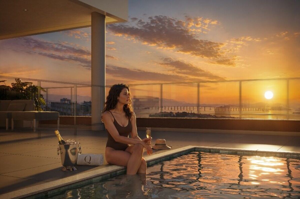 Vista do rooftop do Q Studios ao entardecer, com piscina e vista para a Baía de Guanabara